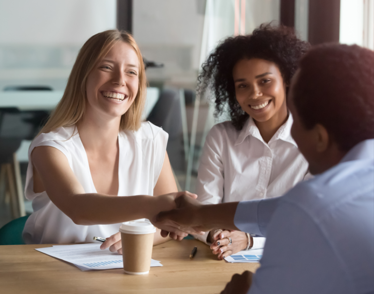 Two people shaking hands with smiles, showing a real connection and trust in a business deal.